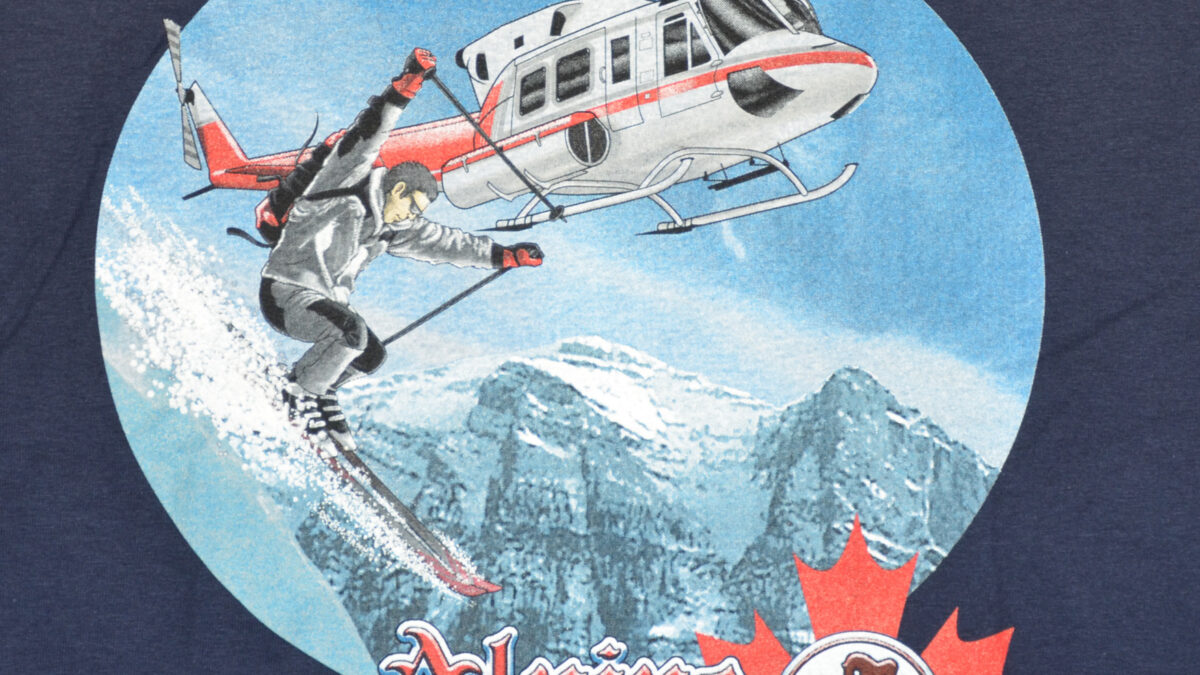 A t-shirt featuring a graphic design of an adventure ski resort, showcasing mountains and skiing elements.