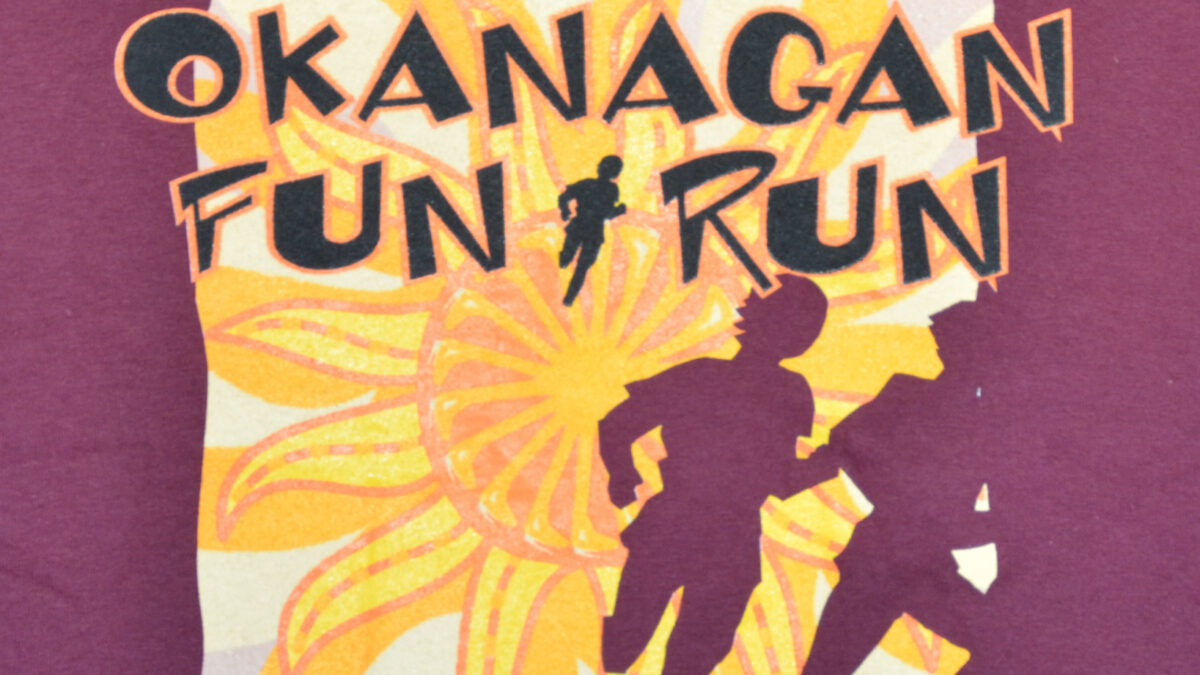 A t-shirt featuring the text "Okanagan Fun Run" in bold, colorful letters on a light background.