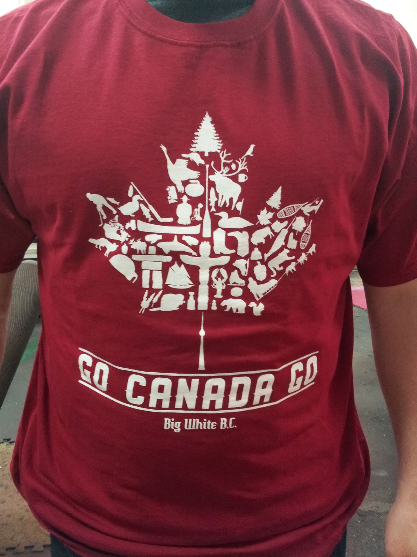 A man in a red t-shirt featuring the Canada logo stands smiling against a neutral background.
