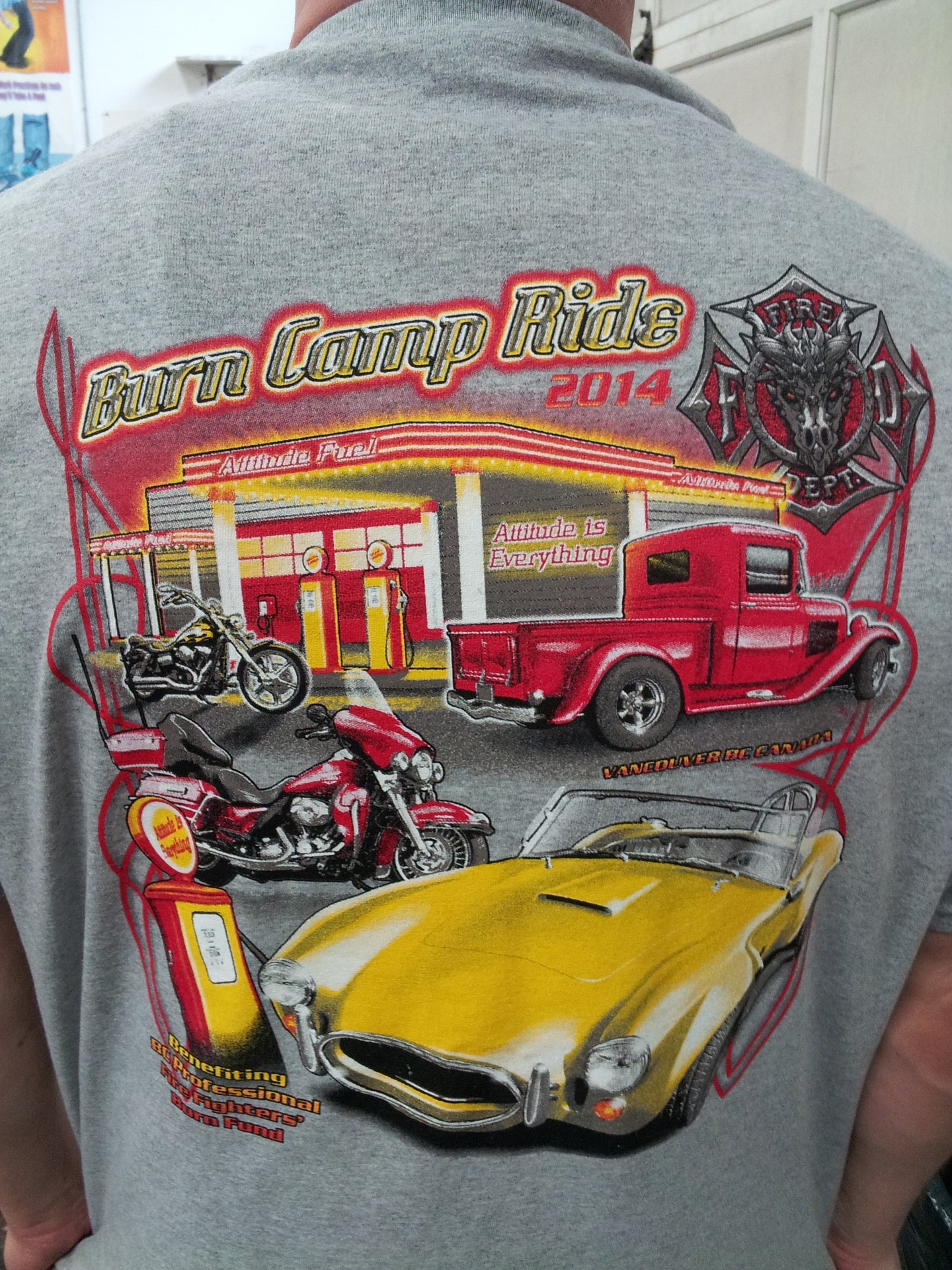 A man in a shirt featuring an image of a car and a truck, standing against a neutral background.